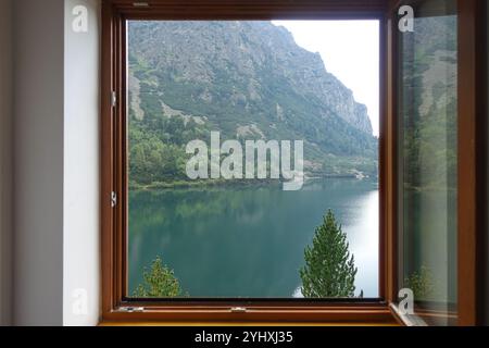 Vue panoramique sur le lac Popradské pleso, Slovaquie, entouré de montagnes et de verdure luxuriante vu à travers une fenêtre ouverte avec un cadre en bois Banque D'Images