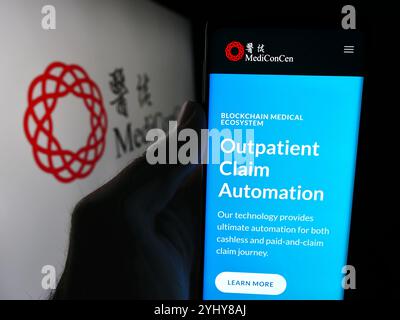 Allemagne. 08 juillet 2024. Dans cette illustration photo, une personne tient un téléphone portable avec la page Web de la compagnie d'assurance blockchain Mediconcen Limited devant le logo. Crédit : SOPA images Limited/Alamy Live News Banque D'Images