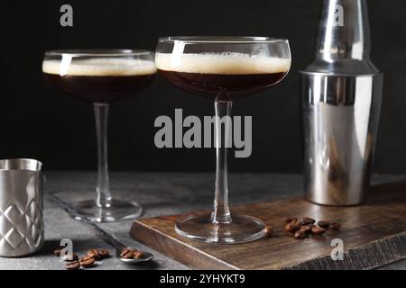 Verres de délicieux espresso martini, shaker et grains de café sur la table à texture foncée, gros plan Banque D'Images