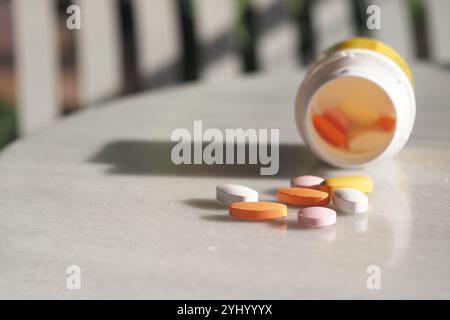 Les pilules sont dispersées et une bouteille ouverte est placée sur la table, suggérant une utilisation récente Banque D'Images