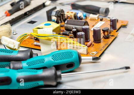 Gros plan des tournevis et de la carte de circuit électronique avec des composants de micropuce, circuits intégrés, condensateurs, résistances et co. Électronique Banque D'Images