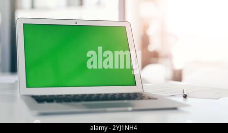 Écran vert, table et ordinateur portable pour espace maquette, promo publicitaire ou espace réservé au bureau. Affichage, ordinateur ou moniteur avec chroma key pour la conception Banque D'Images