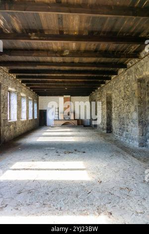 Cheminée en brique orange dans le hall d'une ancienne cave abandonnée. Murs en pierre, grandes fenêtres, plafond en bois Banque D'Images