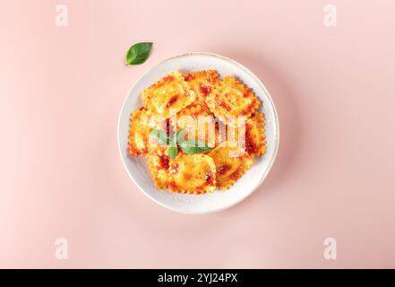Raviolis à la ricotta, sauce tomate fraîche et basilic frais sur fond rose. Vue de dessus. Banque D'Images