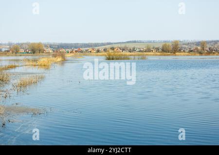 La crue printanière a inondé le champ et la route du village. Eau d'inondation dans les champs, campagne. Arbres dans l'eau. Changement climatique, réchauffement climatique. Globa Banque D'Images