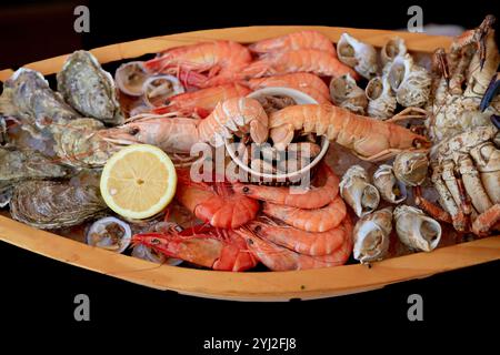 Assiette de fruits de mer frais assortie avec des crevettes, des crabes, des huîtres et une tranche de citron sur une assiette en bois, Portugal Banque D'Images