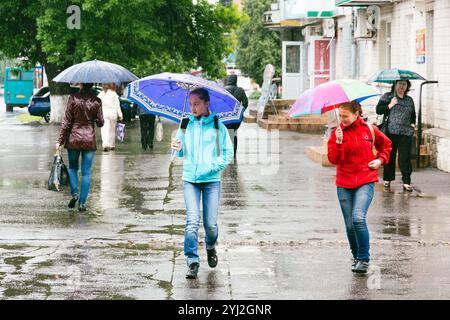 14 mai 2016, Romny, Ukraine : deux jeunes écolières marchent avec des parapluies à l'école dans la rue pendant une forte averse. Banque D'Images