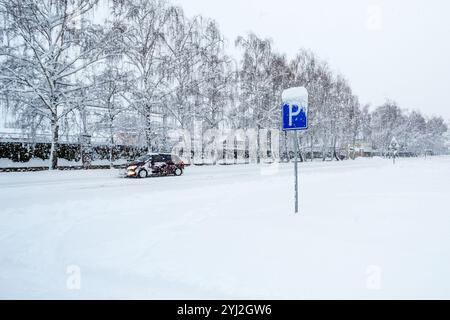 Panneau de signalisation indiquant le stationnement. Panneau de stationnement sur une rue enneigée pendant une chute de neige un jour d'hiver. Parking dans la rue couverte de neige Banque D'Images