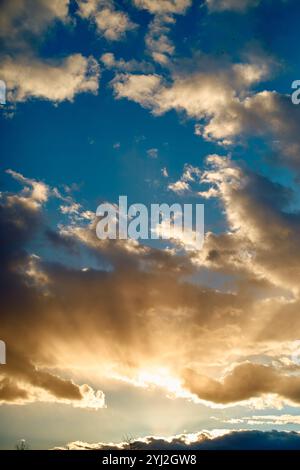 La lumière du soleil éclate à travers des nuages moelleux dans un ciel bleu spectaculaire à l'heure dorée, Berlin, Allemagne Banque D'Images