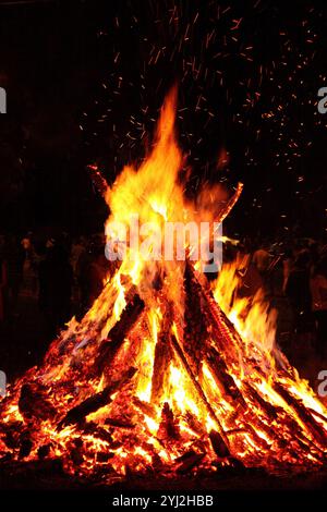 Feu de joie. Grosse flamme orange sur fond noir. Feu sur noir. Lumineux, chaud, léger, camping, grand feu. Des étincelles de feu volantes. Les gens célèbrent Saint Banque D'Images