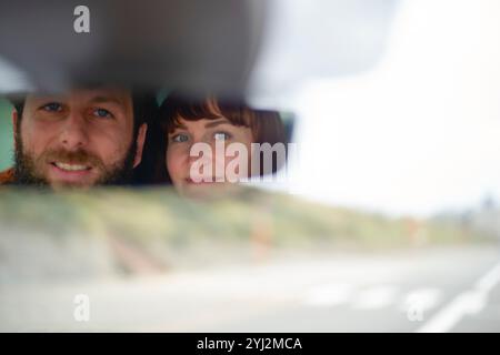 Couple souriant vu à travers un rétroviseur de voiture lors d'un voyage en voiture, Belgique Banque D'Images