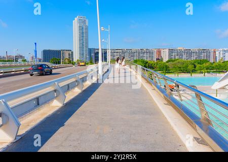 Valence, Espagne - 12 juillet 2024 : passerelle moderne avec des individus marchant, surplombant le paysage urbain de Valence. Banque D'Images