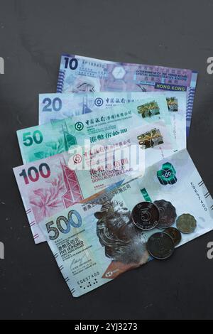 Les billets et les pièces colorés de Hong Kong sont disposés sur une surface plane, mettant en valeur le design distinctif de la monnaie. Banque D'Images