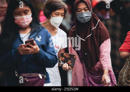 Les foules naviguent dans les rues animées de Hong Kong, mettant en vedette diverses personnes portant des masques lorsqu'elles sont engagées dans leurs activités. Banque D'Images