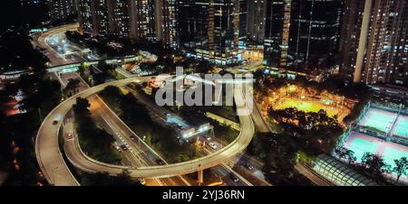 Une vue imprenable sur Hong Kong la nuit avec des bâtiments très éclairés, des routes animées et une activité urbaine animée. Banque D'Images