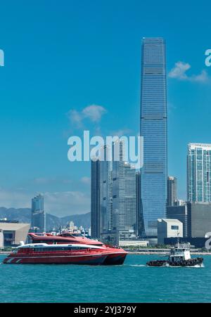Un ferry navigue sur les eaux de Macao à Hong Kong, avec de hauts bâtiments et un ciel bleu clair visible en arrière-plan. Banque D'Images