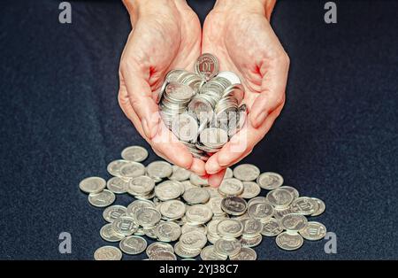 Les paumes féminines tiennent pile de pièces d'argent. Sphère corporative des affaires environnementales. Fond de studio noir Banque D'Images