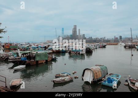 Un port animé de Hong Kong dispose de bateaux traditionnels entourés d'un superbe horizon moderne au crépuscule sous un ciel nuageux. Banque D'Images