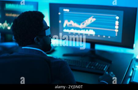 Trader africain travaillant à l'intérieur du bureau la nuit portant casque de réalité virtuelle - Trading and Technology concept - Soft Focus on ear Banque D'Images