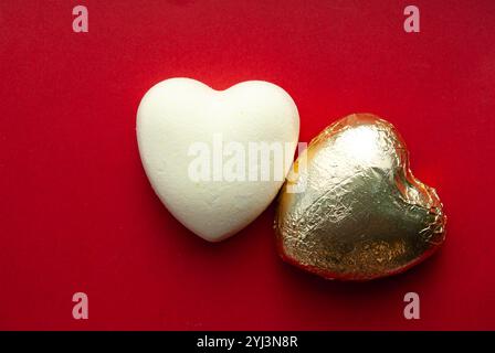 Un coeur en chocolat blanc et or simple mais élégant sur fond rouge, capturant le romantisme. Banque D'Images