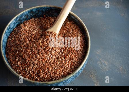 Graines de lin dans un bol bleu avec une cuillère en bois, soulignant la nutrition naturelle. Banque D'Images