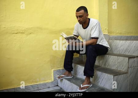 Jorge, un détenu de 29 ans, lit Prisoners de Drauzio Varella, un livre documentaire sur le système pénitentiaire brésilien. Un atelier de lecture a eu lieu au centre de détention Evaristo de Moraes à Rio de Janeiro, au Brésil. Au Brésil, le projet de remise pour lecture vise à réhabiliter les prisonniers en les aidant à réduire leur peine par la lecture de livres. Les autorités espèrent que cela insufflera un amour de la lecture aux détenus et réduira la récidive. Banque D'Images