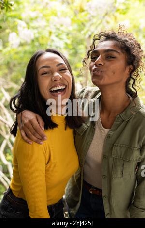 Deux amies féminines multiraciales riant et s'embrassant sur le pont, profitant d'un moment joyeux ensemble Banque D'Images