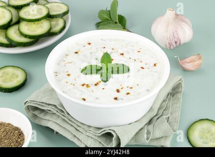 Sauce raita indienne ou tzatziki grecque avec yaourt, concombre et menthe sur fond vert. Banque D'Images