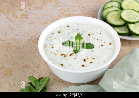 Sauce raita indienne avec yaourt grec, concombre et menthe sur fond jaune. Vue de dessus, espace de copie. Banque D'Images