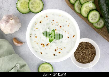 Sauce raita indienne avec yaourt, concombre et herbes sur fond gris. Vue de dessus. Cuisine indienne. Banque D'Images