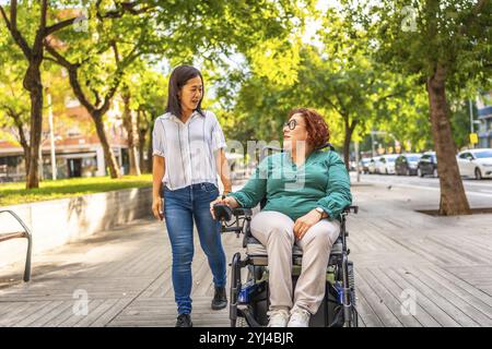 Femme handicapée et amie se promenant le long de la ville dans une journée calme et ensoleillée Banque D'Images