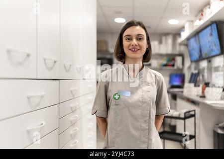 Jeune et fière pharmacienne debout avec les bras à l'arrière dans la salle de stockage dans un magasin moderne Banque D'Images