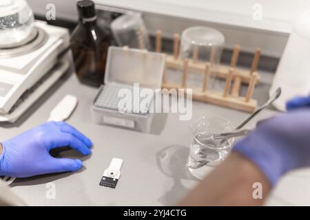 Vue rapprochée en angle élevé des mains gantées d'un médecin analysant des échantillons à l'aide d'une pipette dans un laboratoire de pharmacie Banque D'Images