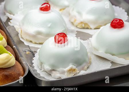 Mini cassata sicilienne avec glaçage blanc et cerise confite sur le dessus exposé dans la pâtisserie Banque D'Images