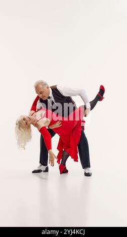 Tango esthétique à travers les années. Vieille belle femme et bel homme senior, couple dansant tango isolé sur fond blanc. Banque D'Images