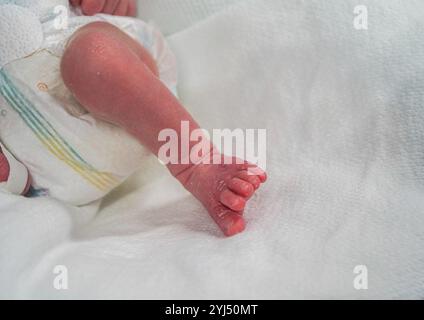 Vue rapprochée d'un bébé prématuré dans l'incubateur et tenu par une mère aimante Banque D'Images