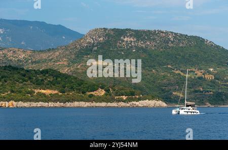 Voilier naviguant sur une vaste mer bleue par une journée ensoleillée avec un ciel nuageux près de la rive de l'île grecque Banque D'Images