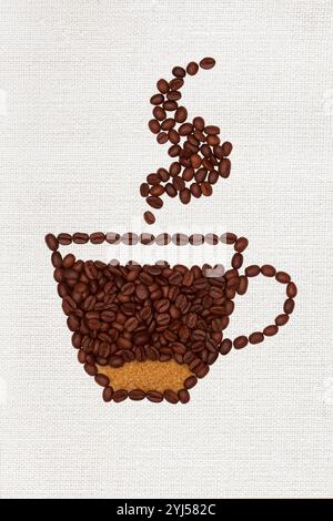 Grains de café et cassonade disposés sous la forme d'une tasse de café avec de la vapeur sur un fond de toile. Banque D'Images