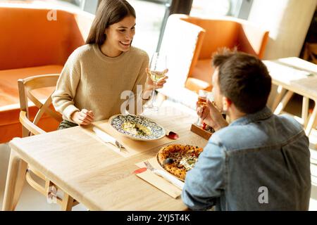 Un couple s'engage dans une conversation animée tout en savourant une délicieuse cuisine dans un restaurant lumineux, partageant des rires et des moments de connexion sur un lei Banque D'Images