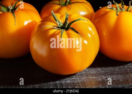 tomate jaune sur fond de bois noir Banque D'Images