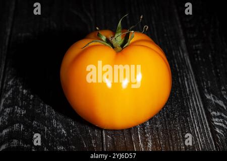 tomate jaune sur fond de bois noir Banque D'Images