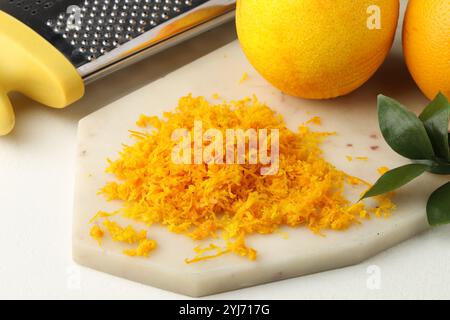 Zeste d'orange frais, râpe et fruits sur la table lumineuse, gros plan Banque D'Images