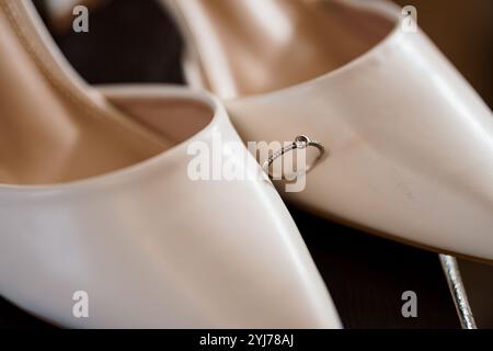 Chaussures de mariage élégantes avec un anneau de fiançailles étincelant. Banque D'Images