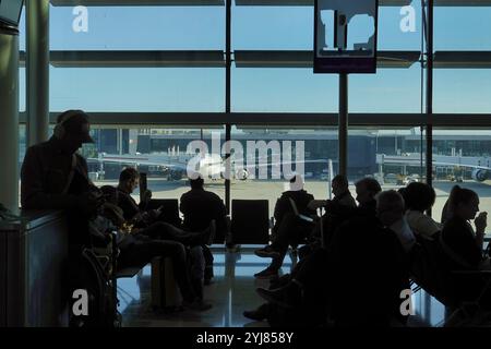 Aéroport de Londres Heathrow, Londres, Royaume-Uni 12 novembre 2024 les passagers / voyageurs (en silhouette) utilisent leurs appareils mobiles en attendant leur fligh Banque D'Images