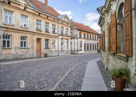 Kuldiga, Lettonie - 3 juillet 2023 : Rue avec de vieilles maisons dans la vieille ville lettone de Kuldiga avec rue pavée. Banque D'Images