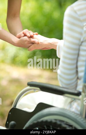 Vieil homme en fauteuil roulant et main d'aide-soignant Banque D'Images