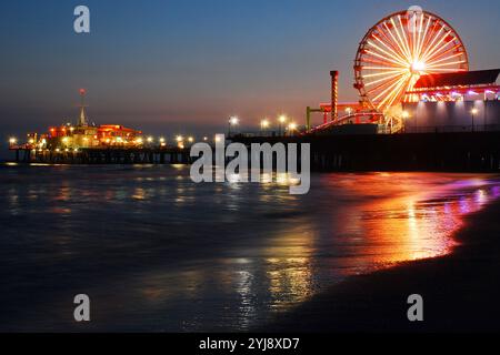 Les lumières de la grande roue et d'autres divertissements sont reflétées int eh les eaux de l'océan à la plage près de la jetée à Santa Monica, en Californie Banque D'Images