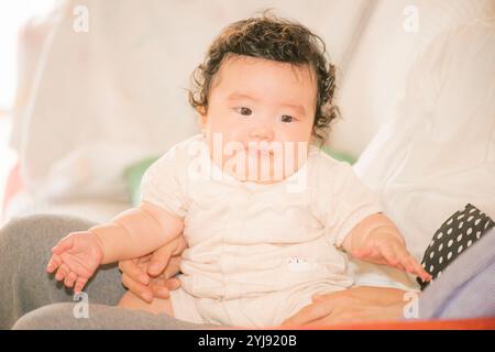 Bébé de cinq mois assis sur les genoux de sa mère Banque D'Images