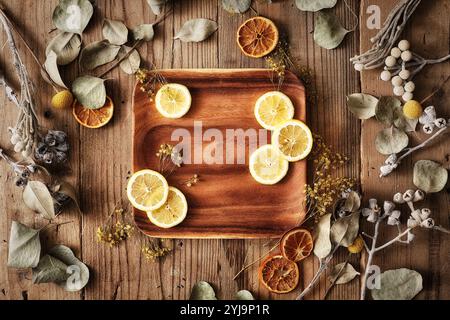 Fleurs séchées et citrons tranchés sur une plaque à pâtisserie en bois Banque D'Images