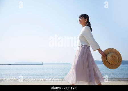 Femme marchant sur le bord de mer Banque D'Images